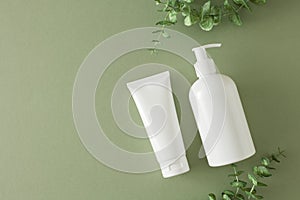 Top view photo of white cream tube, cosmetic bottle and eucalyptus leaves on pastel green background
