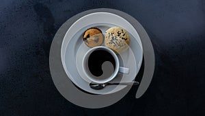 Top view photo, a white cup of americano black coffee, cup cake and cereal bread on white plate on black background
