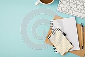 Top view photo of white keyboard cup copybooks and pen on isolated pastel blue background with copyspace