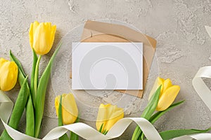 Top view photo of woman`s day composition craft paper envelope and letter bunch of yellow tulips and white ribbon on isolated