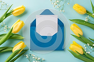 Top view photo of woman`s day composition yellow tulips white gypsophila and open blue envelope with paper sheet on isolated