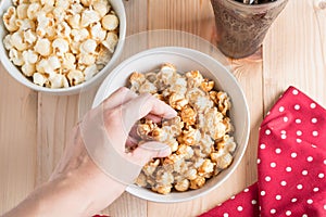 Top view photo of women hand eating popcorn.