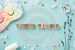 Top view photo of wooden cubes good night text lavender alarm clock multicolored fluffy unicorn sleeping mask earplugs bottle with