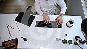Top view of photographer or graphic designer working on white table at his creative workspace.