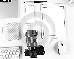 Top view of photographer workplace: Keyboard, tablet, camera and smartphone on white desk background