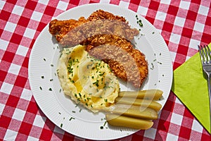 Top view picture on the deep fried chicken escalope or schnitzel with mashed potatoes and pickled cucumbers.