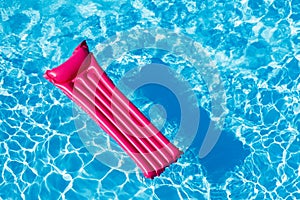 Pink inflatable mattress floating on water surface