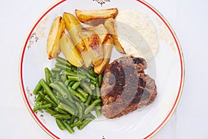 Top view picture on the rustic style porcelain plate with roasted beef steak.