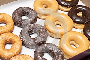Top view picture of variety of assorted glazed donuts in a box. Unhealthy food concept
