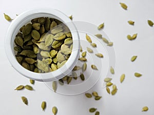 Top view of a pile of green cardamom or cardamon Indian spices on white background.