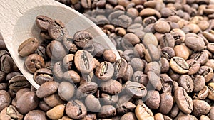 Top view of a pile of scattered aromatic roasted brown coffee beans with a wooden scoop. Coffee beans in a wooden spoon