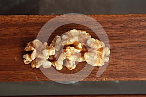 Top view of a pile of walnuts on a wooden surface with a blurry background