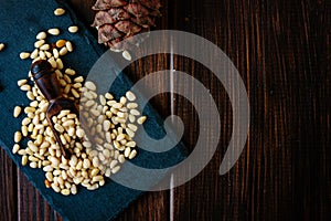 Top view of pine nuts on slate with wooden scoop.