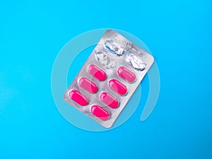 Top view of pink antibiotic pills in gray packaging isolated on a blue background