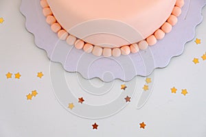 Top view of a pink cake with star shaped confetti aroun