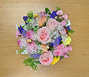 Top view of pink flower bouquet on a wooden board.