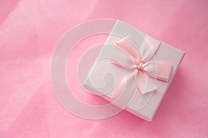 Top view of pink gift box with ribbon bow on pink craft background. Craft pink paper gift box with as a present for Christmas, new