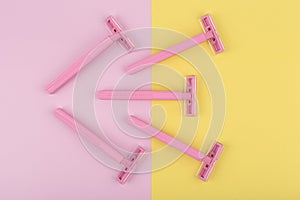 Top view of pink razors for shaving on colored duotone yellow and pink background