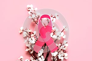 Top view of pink ribbon symbol of breast cancer and white almond blossoms. Breast cancer awareness concept