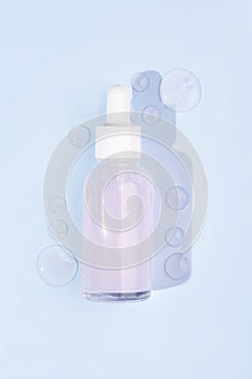 Top view of pink serum essence in glass bottle with smears on blue background. Isolated skincare oil. Beauty treatment