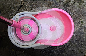 Top view of a pink spin bucket and a mop