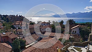 Top view of pivate houses with red tiled roofs and The Mediterranean Sea and mountains in the city of Antalya