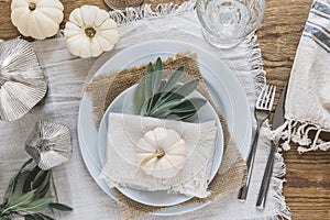 Top view of place setting on a wooden table with white mini pumpkins and sage leaves for Thanksgiving Day or Halloween