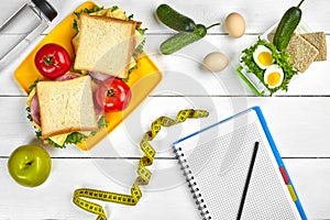 Top view planning notebook with copy space and healthy breakfast. Sandwich with ham and cheese, eggs, cucumber, tomato