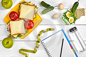 Top view planning notebook with copy space and healthy breakfast. Sandwich with ham and cheese, eggs, cucumber, tomato