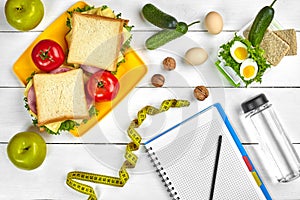 Top view planning notebook with copy space and healthy breakfast. Sandwich with ham and cheese, eggs, cucumber, tomato