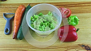 Top view on plastic bowl with chopped green lettuce and different vegetables