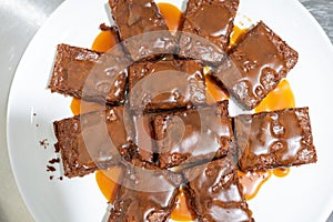 Top view on a plate with brownie pieces poured with salted caramel sauce