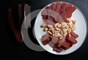 Top view of a plate with dried tuna and dried fish roe with fried almonds on black background