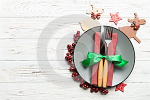 Top view of plate, fork and knife served on Christmas decorated wooden background. New Year Eve concept with copy space