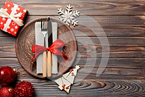 Top view of plate, fork and knife served on Christmas decorated wooden background. New Year Eve concept with copy space