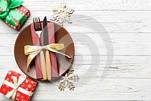 Top view of plate, fork and knife served on Christmas decorated wooden background. New Year Eve concept with copy space