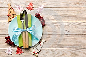 Top view of plate, fork and knife served on Christmas decorated wooden background. New Year Eve concept with copy space