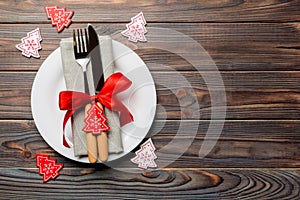 Top view of plate, fork and knife served on Christmas decorated wooden background. New Year Eve concept with copy space