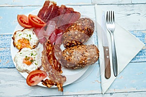 Top view on plate with fried eggs, bacon, tomato and buns, Chrono diet concept