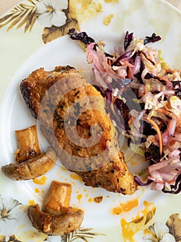 Top view on a plate with fried juicy pork, two half of champignon and cabbage salad