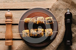 top view of plate with grilled corn between salt and pepper grinders on wooden table