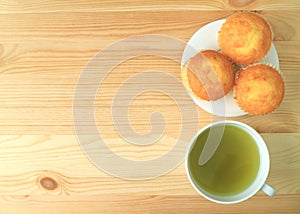 Top View of a Plate of Madeleine Cupcakes Served with a Cup of Green Tea on Wooden Table