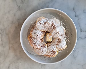Top view of a plate of puffertjes on a keramic table. Copy space