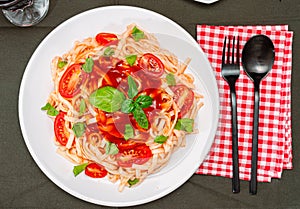 Top view of a plate of spaghetti pasta with a delicious tomato sauce with basil leaves. Natural and homemade food concept