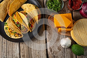 Top view of plate with tasty mexican tacos on rustic wooden table with ingredients for cooking background. Concept of traditional