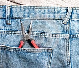 Top view Pliers in denim pants pocket. The concept of repair and construction, construction tools in the pocket of the chaton photo