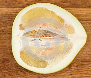 Top view of pomelo fruit half on wooden cutting board