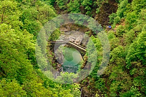 Top view on the Ponte Romano Intragna Bridge hiding in the valley with beautiful river covered with trees, close to