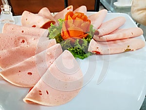 Top view of pork ham sliced or bologna with lettuce and carrot on white plate photo