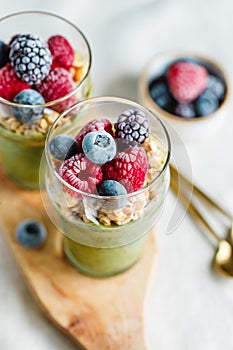 Top view on portions of chia pudding with matcha tea, organic granola, frozen berries in glasses